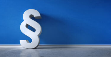 Paragraphen-Symbol vor blauer Wand.