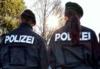 Polizeibeamte von hinten, die Demonstranten gegenüberstehen.