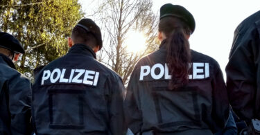 Polizeibeamte von hinten, die Demonstranten gegenüberstehen.