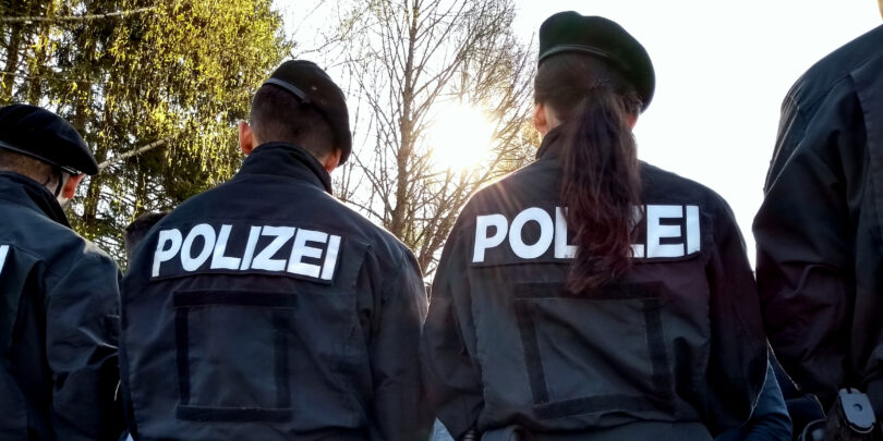 Polizeibeamte von hinten, die Demonstranten gegenüberstehen.
