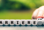 Nahaufnahme einer Hand, die in einer Reihe beschrifteter Würfeln zwei davon umdreht und so das Wort "Barriere" in "barrierefrei" ändert.