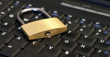 Nahaufnahme von Vorhängeschloss auf Laptoptastatur.
