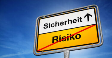 Fiktives quadratisches Verkehrsschild. In der oberen Hälfte steht Sicherheit, daneben ein Pfeil nach oben. In der Hälfte steht das Wort Risiko. Dieses ist mit einer diagonalen roten Linie durchgestrichen.