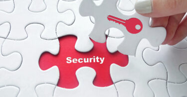 Close up of girl's hand placing the last jigsaw puzzle piece with word security and key icon as security concept.
