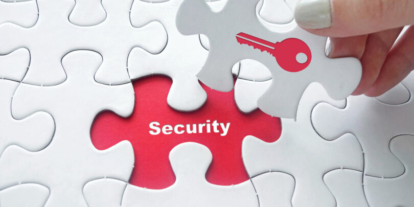Close up of girl's hand placing the last jigsaw puzzle piece with word security and key icon as security concept.
