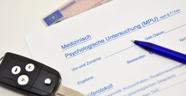 Oberer Teil eines Medizinisch-psychologischen Gutachtens. Darauf liegen ein Autoschlüssel und ein Stift. Darunter liegt, halb verdeckt, ein Führerschein.