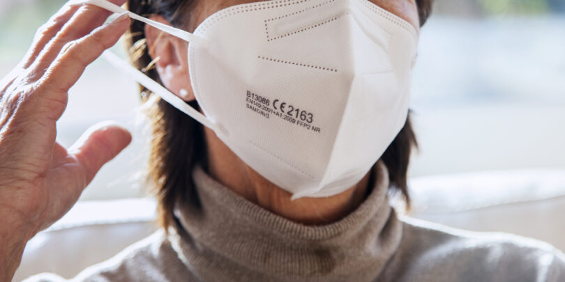 Nahaufnahme der Mund-Nasen-Partie einer Frau, die gerade eine FFP-2-Maske aufzieht.