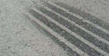 Nahaufnahme einer Bremsspur auf grauem Asphalt.