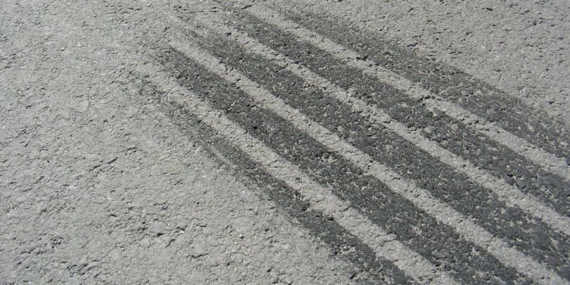 Nahaufnahme einer Bremsspur auf grauem Asphalt.