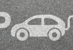 Zeichnung auf Asphalt, bestehend aus einem großen P für "Parkplatz" sowie der schematischen Darstellung eines Elektrofahrzeugs.