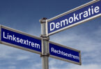 Verkehrsschild für Straßen: Es hat drei Straßennamen. Auf einem steht Demokratie, auf dem anderen Linksextrem und auf dem letzten Rechtsextrem.