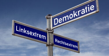 Verkehrsschild für Straßen: Es hat drei Straßennamen. Auf einem steht Demokratie, auf dem anderen Linksextrem und auf dem letzten Rechtsextrem.