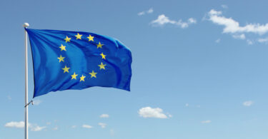 EU flag waving against blue sky with clouds.