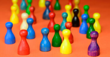 Ansammlung verschieden farbiger Mensch-ärgere-dich-nicht-Spielfiguren.