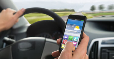 Close-up Of A Person's Hand Using Cellphone While Driving A Car.