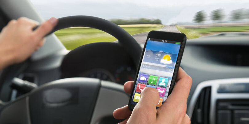 Close-up Of A Person's Hand Using Cellphone While Driving A Car.