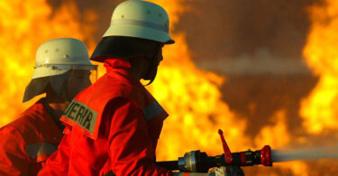 Zwei Feuerwehrmänner, die einen Brand bekämpfen.