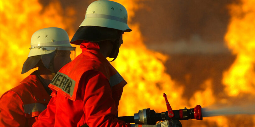 Zwei Feuerwehrmänner, die einen Brand bekämpfen.