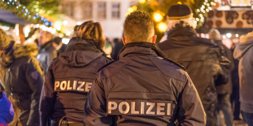 Drei Polizeibeamte von hinten auf einem Weihnachtsmarkt.
