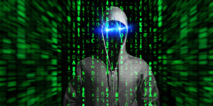 Virtueller Raum, aus dem sich eine bedrohliche Gestalt herausbildet, deren Gesicht von einer Kapuze verschattet ist und die blau leuchtende Augen hat.