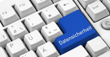Nahaufnahme einer grauen Tastatur mit blauer Eingabetaste, auf der in weißer Schrift "Datensicherheit" steht.