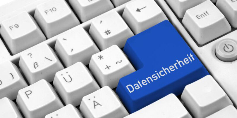 Nahaufnahme einer grauen Tastatur mit blauer Eingabetaste, auf der in weißer Schrift "Datensicherheit" steht.