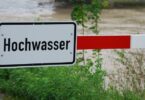 Heruntergelassene Schranke, an der ein Schild mit der Aufschrift Hochwasser angebracht ist.