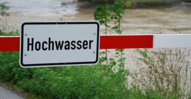 Heruntergelassene Schranke, an der ein Schild mit der Aufschrift Hochwasser angebracht ist.