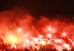 Fanblock in einem Fußballstadion, in dem Bengalos gezündet werden.