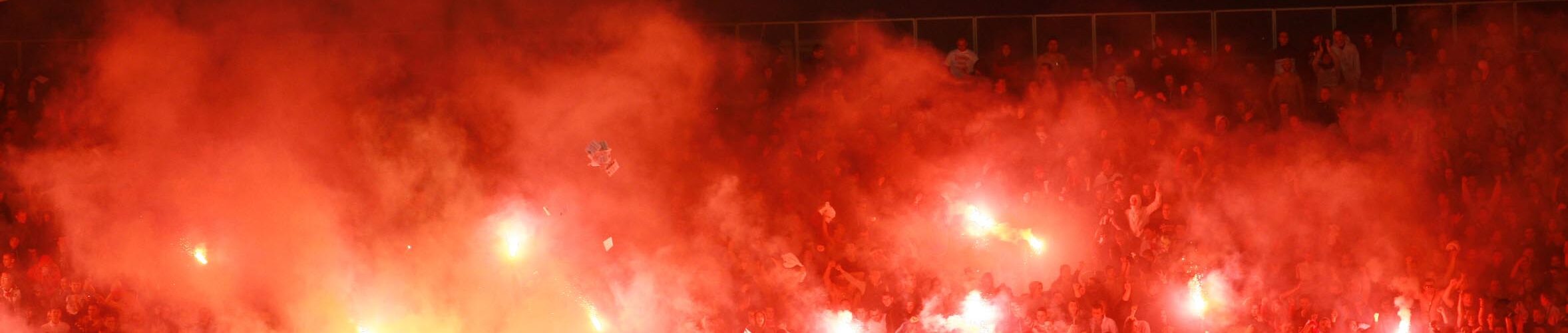 Fanblock in einem Fußballstadion, in dem Bengalos gezündet werden.