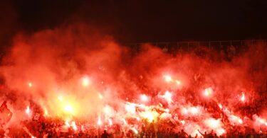 Fanblock in einem Fußballstadion, in dem Bengalos gezündet werden.