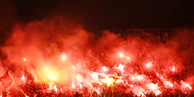 Fanblock in einem Fußballstadion, in dem Bengalos gezündet werden.
