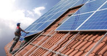 Monteure bringen PV-Module auf einem Dach an.