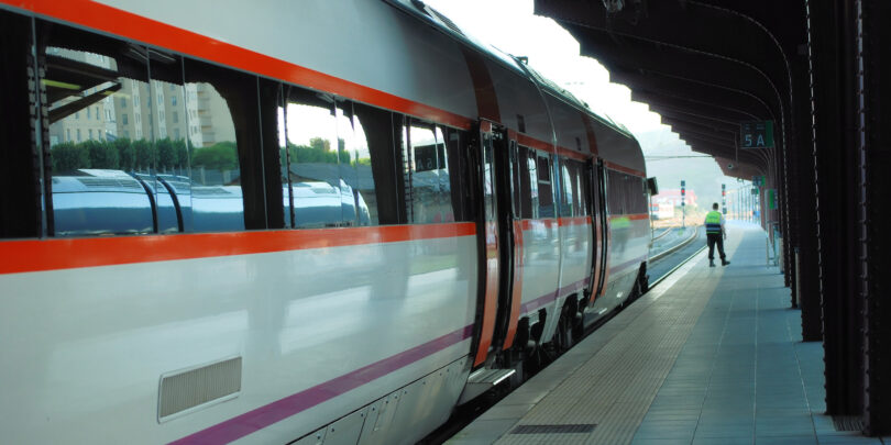Zug am Bahnsteig, auf dem im Hintergrund ein Polizist steht.