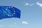 EU flag waving against blue sky with clouds.
