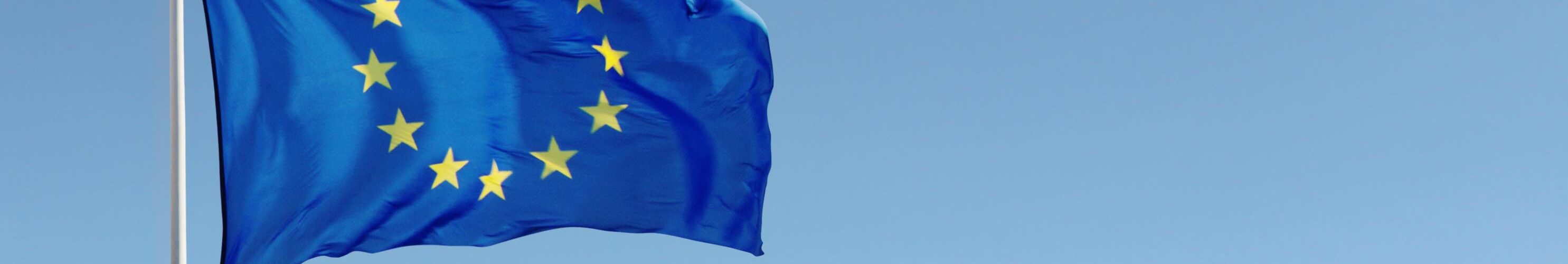EU flag waving against blue sky with clouds.