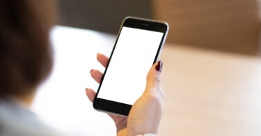 Smartphone mockup image of a woman's hand holding mobile phone with blank screen.