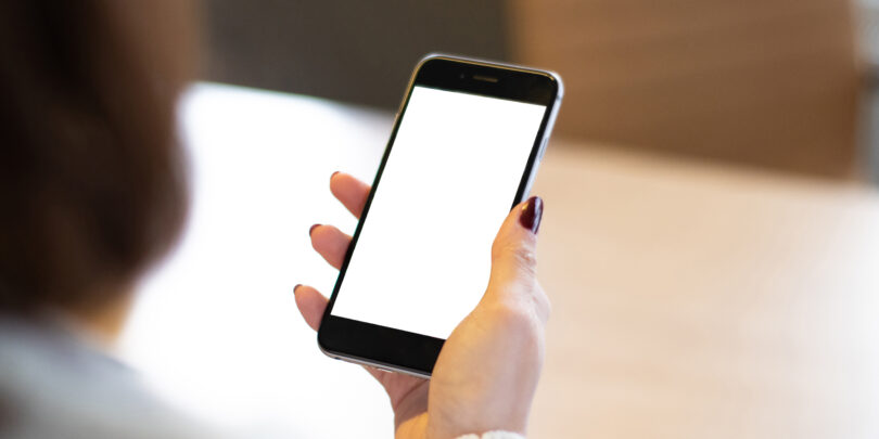 Smartphone mockup image of a woman's hand holding mobile phone with blank screen.
