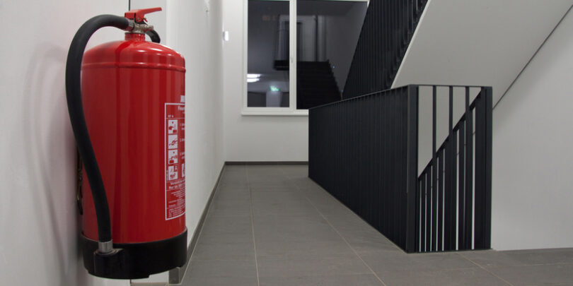Feuerlöscher, der an der Wand eines Treppenhauses befestigt ist.