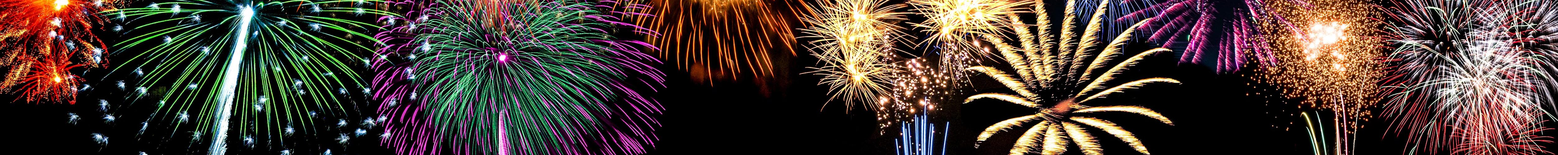 Explodierende Feuerwerkskörper vor schwarzem Nachthimmel.