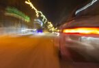 The car is driving at high speed on the night street of the city. Blurred image along the lines of the road with zoom.