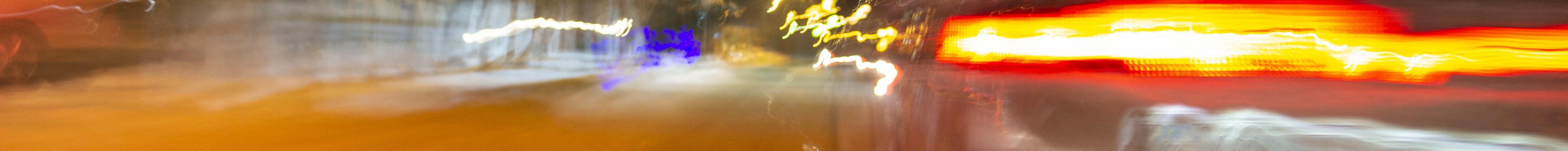 The car is driving at high speed on the night street of the city. Blurred image along the lines of the road with zoom.