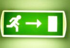 Grün leuchtendes Fluchtwegschild vor grünem Hintergrund.