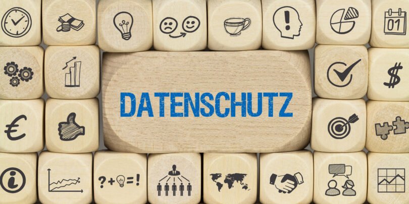 Übereinander gestapelte Würfel mit Symbolen, wobei auf dem mittleren Würfel "Datenschutz" steht.