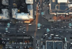 Aerial view of city intersection with many cars and GPS navigation system symbols. Autonomous driverless vehicles in city traffic.