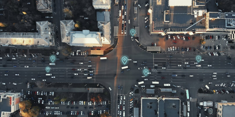 Aerial view of city intersection with many cars and GPS navigation system symbols. Autonomous driverless vehicles in city traffic.