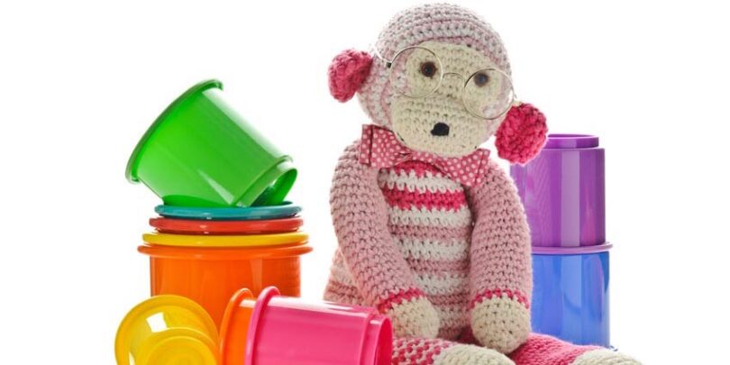 Ansammlung von Spielzeug, in deren Mitte sich ein Kuscheltieraffe befindet.