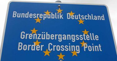 Blaues Schild, das eine EU-Grenzübergangsstelle ausweist. Die Aufschrift lautet: "Bundesrepublik Deutschland. Grenzübergangsstelle. Border Crossing Point".