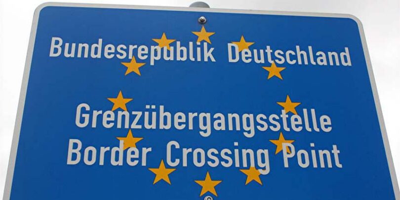 Blaues Schild, das eine EU-Grenzübergangsstelle ausweist. Die Aufschrift lautet: "Bundesrepublik Deutschland. Grenzübergangsstelle. Border Crossing Point".