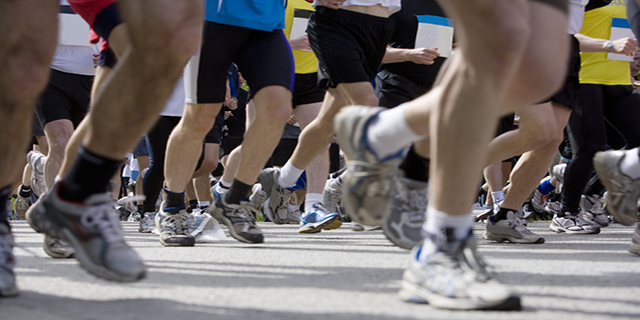 Beine mehrerer Teilnehmer an einem Marathonlauf.